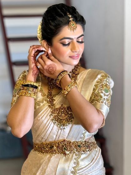 A candid moment of the bride getting ready. This shot highlights the intricate details of her jewelry and the flawless application of her makeup.