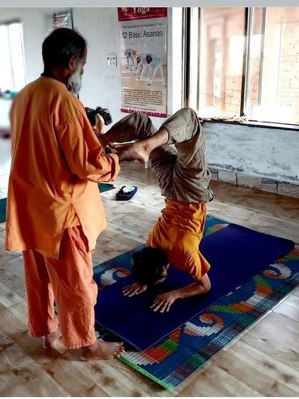 Assisting a student in our Level 1 YTTC with an advanced variation. Even in the foundational course, we encourage students to safely explore their limits with personalized guidance.