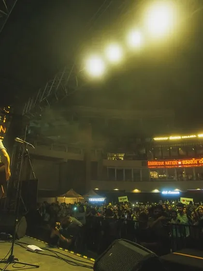 An artist stands before a massive crowd in an open-air amphitheater setting. I am experienced in managing events in large, multi-level venues, ensuring great sound and views from every angle.