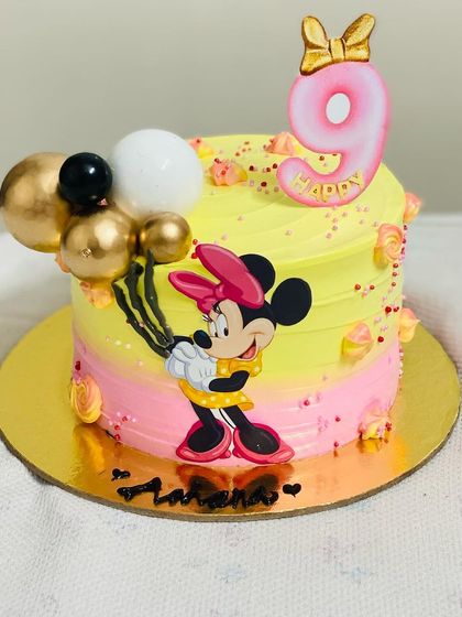 A cute Minnie Mouse cake with a yellow and pink design for a 9-month celebration.