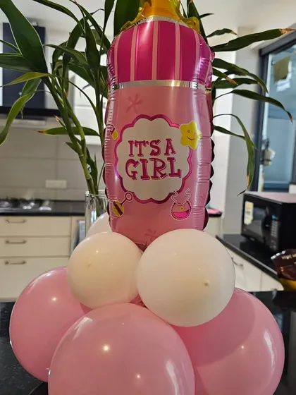 An 'It's a Girl' baby bottle foil balloon arrangement. This is a classic and fun way to announce the baby's gender at a party.