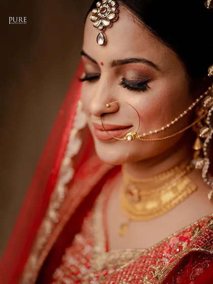A close-up portrait of the bride, highlighting her flawless makeup, the intricate design of her nath, and her calm expression.