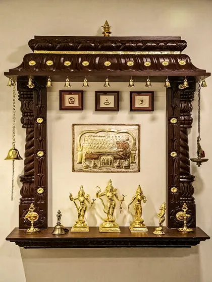 We also create timeless, traditional pooja units. This wall-mounted mandir is crafted from dark, polished wood with intricate carvings along the top, reminiscent of South Indian temple architecture. It features classic brass bells and provides a beautiful, space-saving solution for honoring tradition in any home.