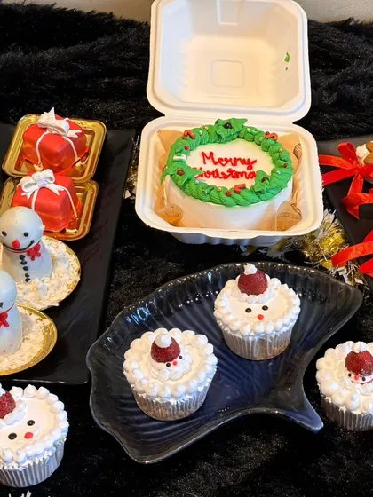 Our Christmas goodies spread, featuring a "Merry Christmas" bento cake, Santa-themed cupcakes, snowman desserts, and gift-box pastries. A festive treat for everyone.