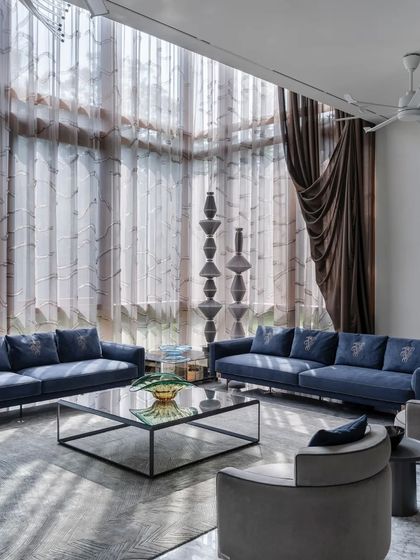 The formal living room features double-height ceilings with dramatic curtains, creating a sense of grandeur and opulence.