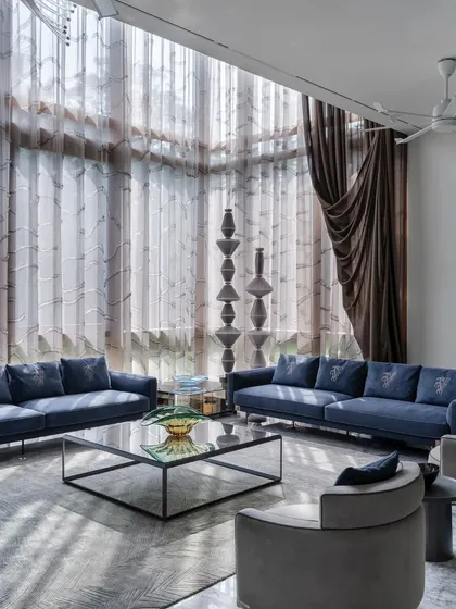 The formal living room features double-height ceilings with dramatic curtains, creating a sense of grandeur and opulence.