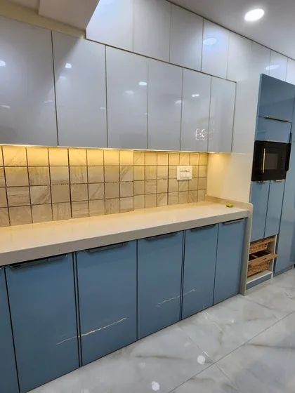 A view of the other side of the parallel kitchen, showing the tall unit with an integrated microwave and pull-out wicker baskets.