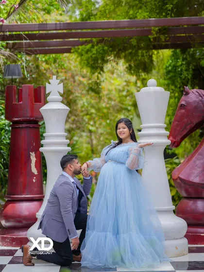 A royal-themed pose on the giant chessboard, with the partner kneeling and kissing the mother-to-be's hand.