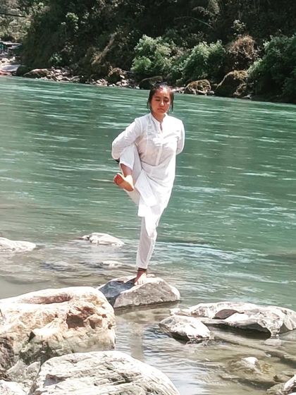 A balancing pose with closed eyes on an uneven surface by the river. This is a true test of mental calm and focus, the essence of yoga.