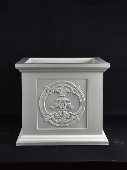 An ornate, square fiber planter with a decorative emblem. This type of pot is ideal for traditional or classic garden designs.