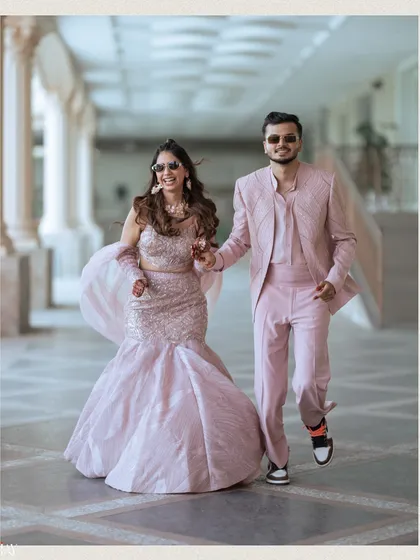 A fun and energetic shot of the couple running towards the camera, hand in hand. Their matching pink outfits and sunglasses perfectly suit the lively, carnival theme of their outdoor event.