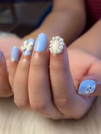 A close-up of the intricate pearl frame and 3D bow on the coquette nail set.