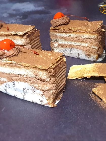 Slices of our Napoleon pastry. This dessert features layers of flaky puff pastry and rich chocolate cream, topped with cocoa powder and a cherry.