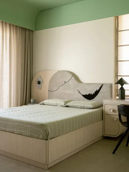 This bedroom in the 'Soft Serve' project features a playful pop of green and a whimsical headboard doodle. The design balances the home's otherwise tone-on-tone palette with curves, textures, and a touch of fun.