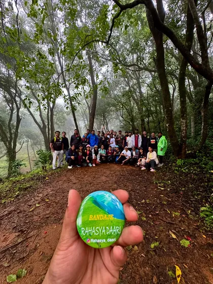 A shot combining our signature badge with the group in the background, deep within the misty forests of the Bandaje trek.