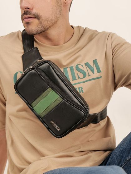 A model wearing a modern, black and green crossbody bag, showing its scale and position when worn.