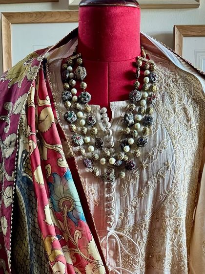 A full-length view of the Achkan Anarkali on a mannequin, styled with a statement necklace and a vibrant Kalamkari dupatta to showcase its versatility.