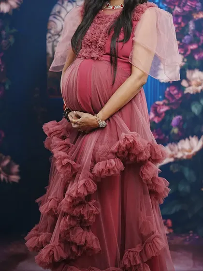 This pastel onion pink gown with delicate flutter sleeves is a soft and flowy option for a maternity photoshoot. It's available to rent with matching jewelry.