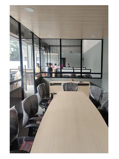 A look inside the conference room during setup. The large windows provide a view of the surrounding greenery, connecting the indoor workspace with the outdoors.