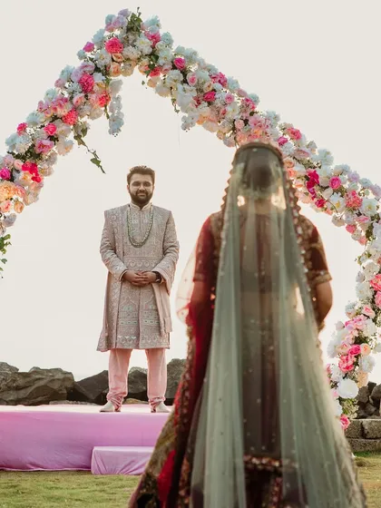 The groom's anticipation is a story in itself. I carefully stage the bridal entry to create a powerful first look moment, where he sees his bride approaching against a beautifully designed floral arch.