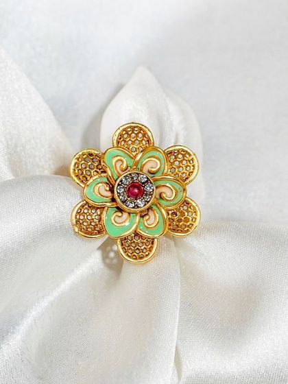 A traditional floral ring styled on a soft, white silk cloth. The texture of the fabric adds a sense of luxury and elegance to the photo.