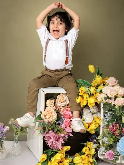 A joyful, energetic pose from the same boy, showing his excitement during the floral-themed shoot.