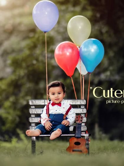 Cuteness overload, picture perfect moments. A stylishly dressed little boy sits on a park bench with his ukulele and balloons.