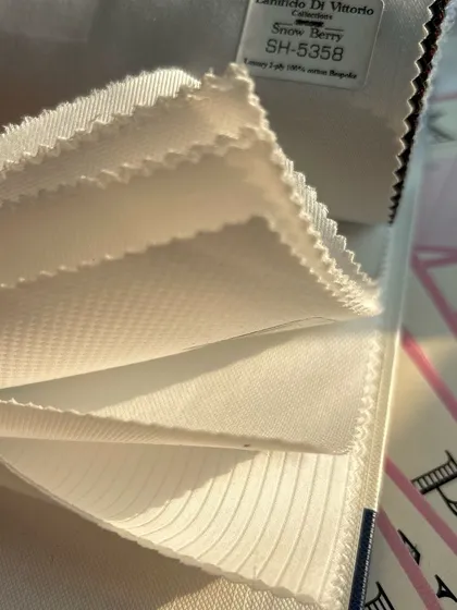 A fanned-out book of white shirting fabrics, showing the variety of textures and weaves we offer.