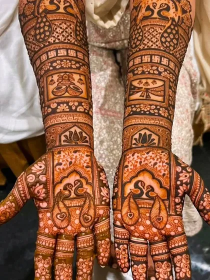 This bridal design features peacocks on the palms and auspicious swastika symbols on the arms, combining beauty with tradition.