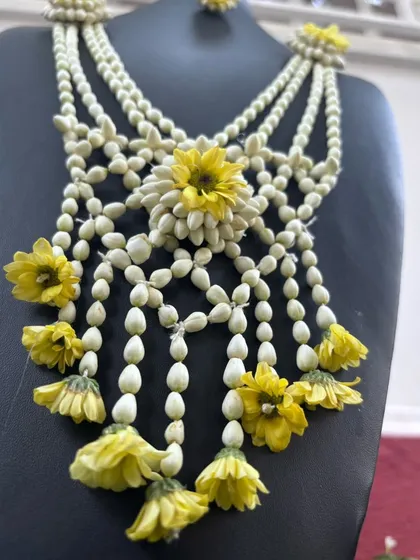 This unique floral necklace is made from mogra buds and accented with yellow flowers, creating a beautiful cascading design. It's a piece that is sure to make you feel special.