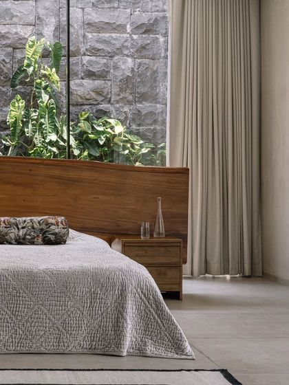 The bed in the master suite is positioned to offer a direct view of the private courtyard. The full-height window and sheer curtains allow for a soft, diffused light to fill the room.