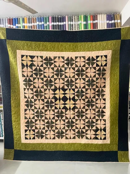 A "Wheel of Mystery" quilt with a complex geometric pattern in earthy tones.