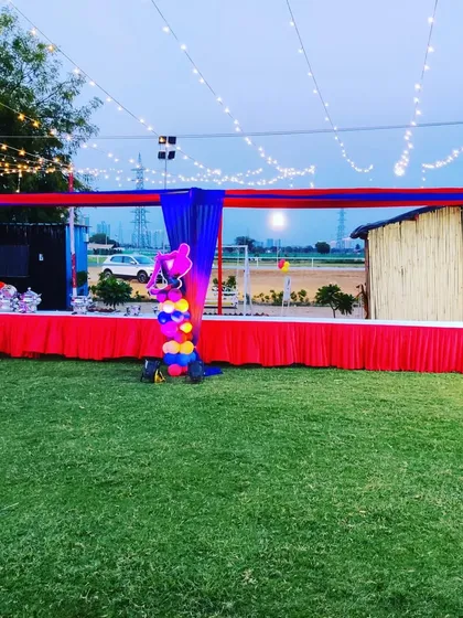 Another view of the large-scale setup at a farmhouse birthday party, showing the buffet line, decorative balloon pillar, and the vast lawn space prepared for the event.