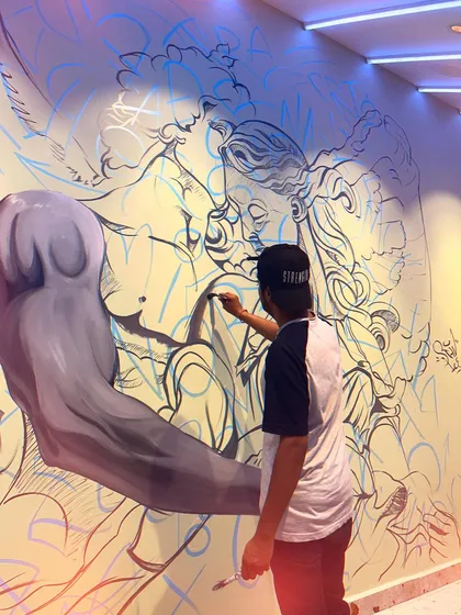 A low-angle shot of me working on the angelic couple mural. This perspective emphasizes the size of the artwork and the focus required to paint such a detailed piece.