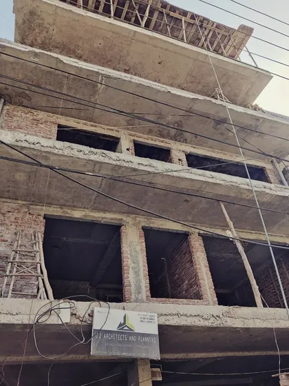 A building under construction, with our firm's board displayed prominently. This shows an early stage, with the brickwork and concrete structure exposed.