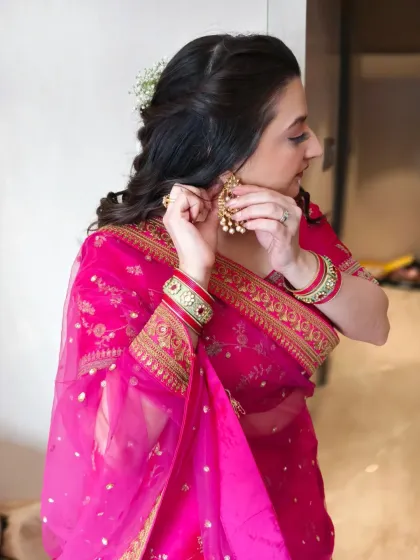 The final touches make all the difference. This candid shot shows the client putting on her earrings, with her soft curls and glowing makeup completing the festive look.