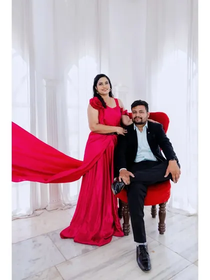 A regal-looking portrait of the couple. The bride's flowing red dress and the groom's confident pose on the throne chair create a powerful image.