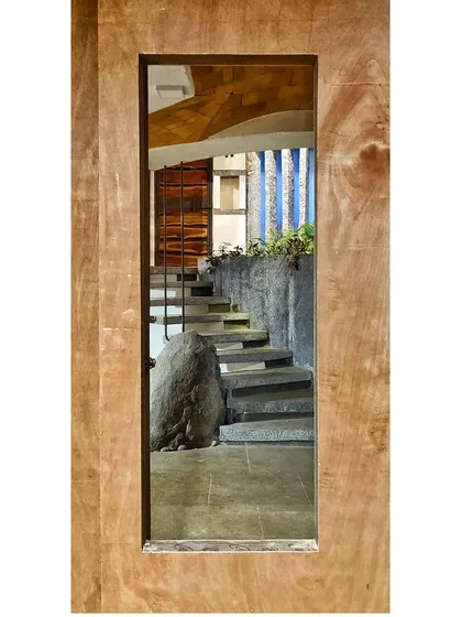 A view framed in wood captures the essence of this stone staircase. The natural boulder at its base serves as a surprising and organic element, grounding the design in the earth.