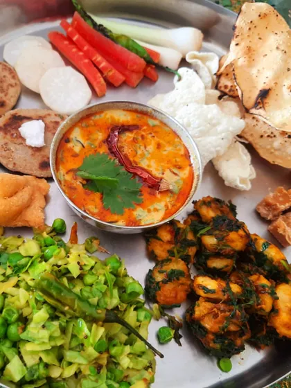 A wholesome and traditional Gujarati winter thali. This plate features bajra roti with a dollop of vegan white butter, dahi tikhari made with soy-cashew curd, seasonal vegetables, and more. It's a complete, soulful meal.
