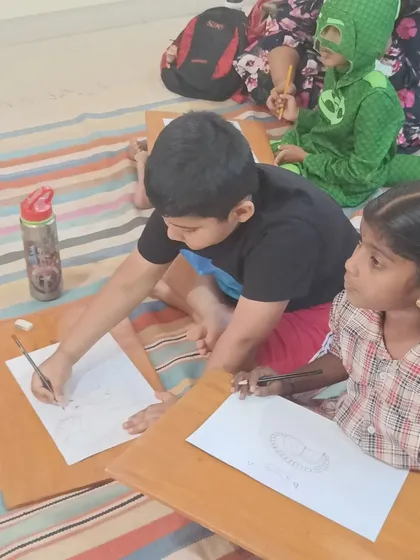 Children practice their drawing skills, following the storyteller's demonstration on their own papers.