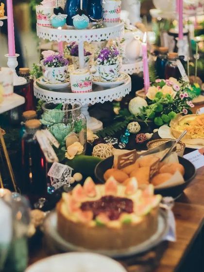 A full view of the whimsical brunch setup. The dessert and food table was a feast for the eyes, laden with themed treats, floral arrangements, and charmingly mismatched crockery to capture the delightful chaos of a mad tea party.
