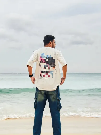 A back view of a graphic tee from Hubberholme, set against the ocean. This type of shot focuses on the product's design details while maintaining an aspirational travel vibe.