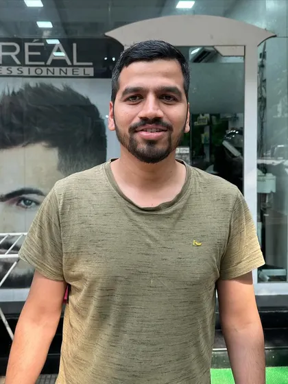 A happy client standing in front of the salon, showing his fresh cut and beard trim.