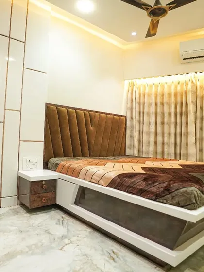 This master bedroom design balances modern and classic elements. It features a custom bed with an upholstered headboard and a high-gloss white wardrobe with subtle gold inlay details.