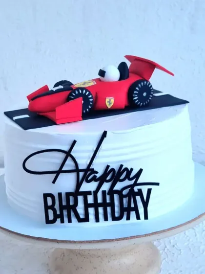 A sleek birthday cake with a hand-sculpted fondant Ferrari topper. Even on a simple whipping cream base, a detailed topper can make a big impact.
