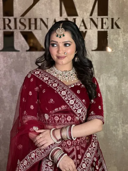 A happy client in our maroon velvet lehenga, paired with a beautiful diamond and emerald necklace set.