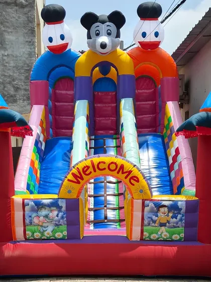 A front view of our 12x18 foot 3-slider bouncy castle. This model features a central climbing ladder and three slides, all made with high-quality, brightly colored SRF fabric.