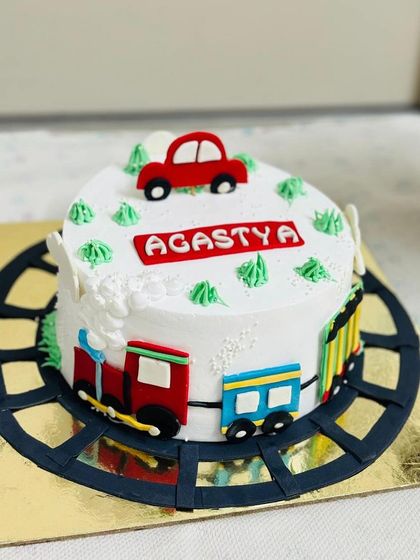 A fun train-themed cake with a toy car on top, designed for a child who loves vehicles.