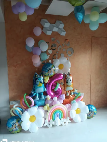 A cute and colorful Bluey-themed balloon arrangement for a 6th birthday. It features character foil balloons, daisy-shaped balloons, and a mini rainbow.