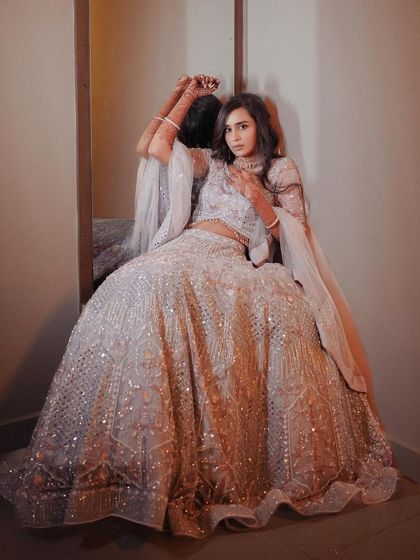 The bride posing against a mirror, her elegant lehenga and confident pose creating a stunning reflection.